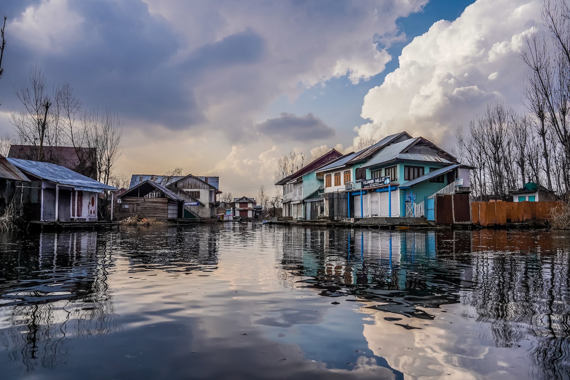 blue and white wooden houses beside river under blue and white cloudy sky