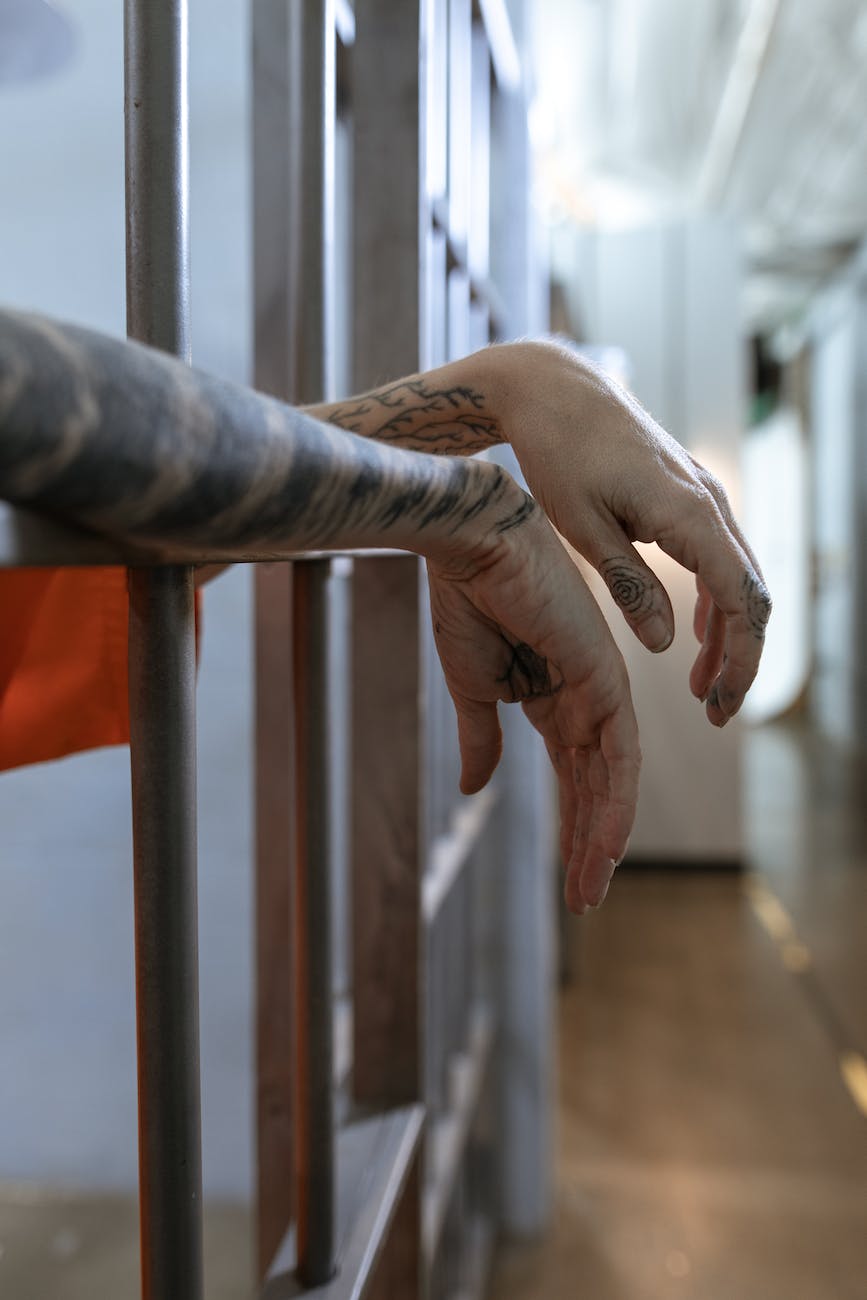 hands of a person hanging from steel bars in jail or prison (Photo by RDNE Stock project)