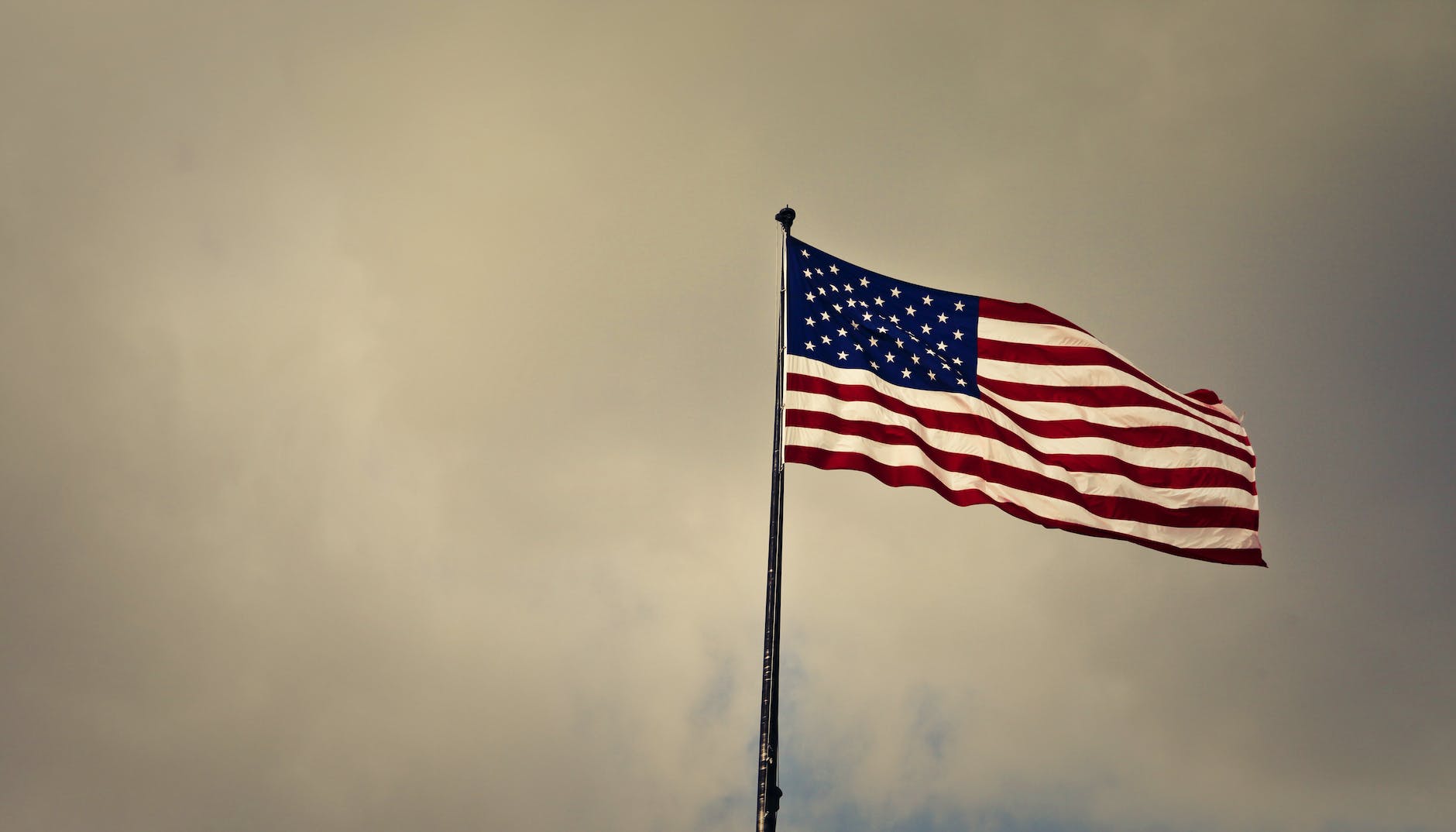 photo of cloudy skies over american flag (Photo by Andrea Piacquadio)